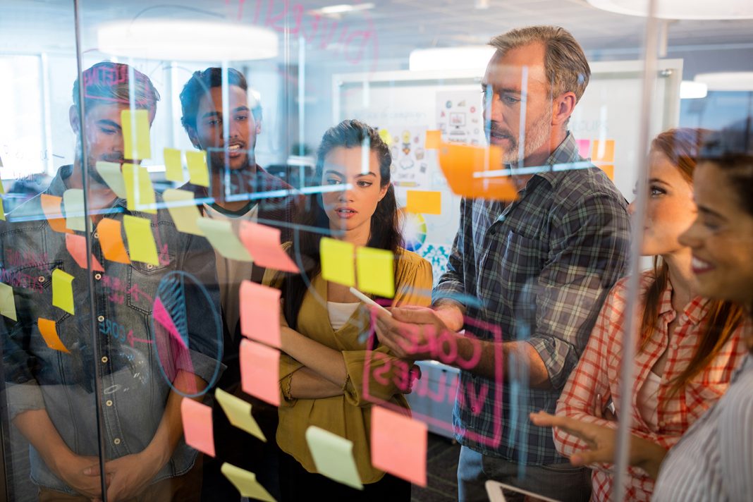 Creative business team looking at sticky notes on glass window